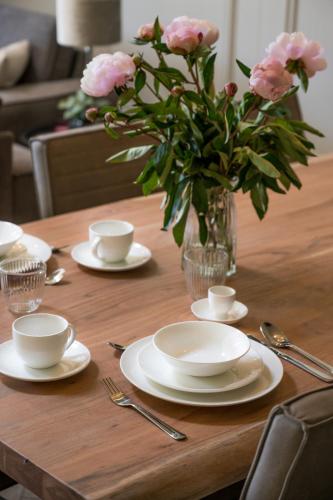 a wooden table with plates and a vase of pink flowers at Holiday home de Stamhoeve in Biezenmortel