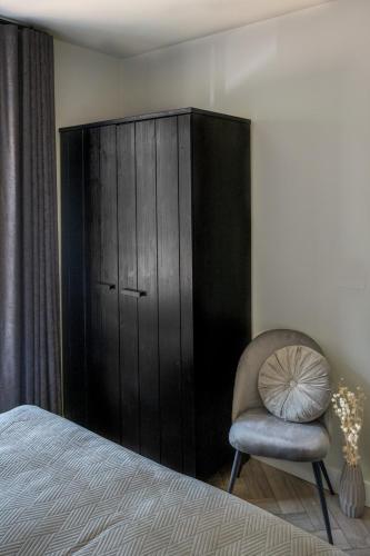 a bedroom with a chair and a black cabinet at Holiday home de Stamhoeve in Biezenmortel