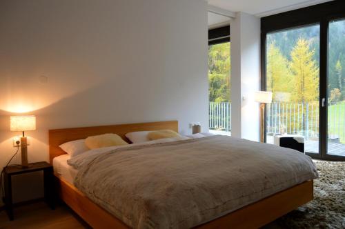 a bedroom with a large bed and a large window at Schooren des Alpes - Apartment LES CAVES DU ROI- TOP 1 in Kappl
