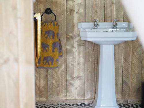 a bathroom with a sink and a towel hanging on a wall at Brackenhill Glamping - Safari Tent with Hot Tub - Sleeps 6 in Ivybridge
