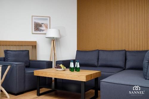 a living room with a couch and two bottles on a table at Apartament Premium Marin - Pinea Apartments Pobierowo in Pobierowo