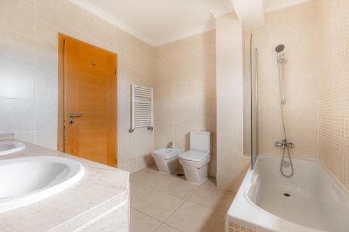 une salle de bain avec une baignoire, des toilettes et un lavabo dans l'établissement Dunas Triplex, à Lagos