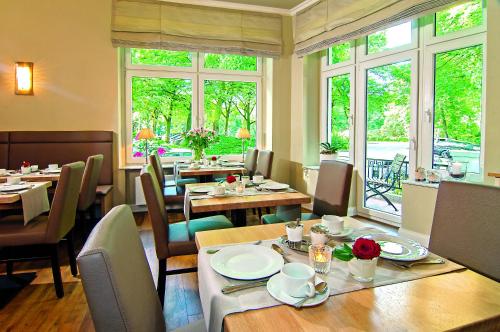 a restaurant with tables and chairs and windows at Hotel Mare in Hamburg