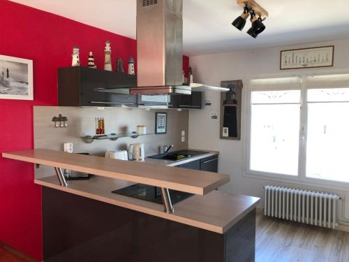 cocina con paredes rojas y encimera de madera en La Maison des phares, en Lion-sur-Mer