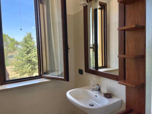 a bathroom with a sink and two windows at Agriturismo con cucina Il Favaio in Paciano
