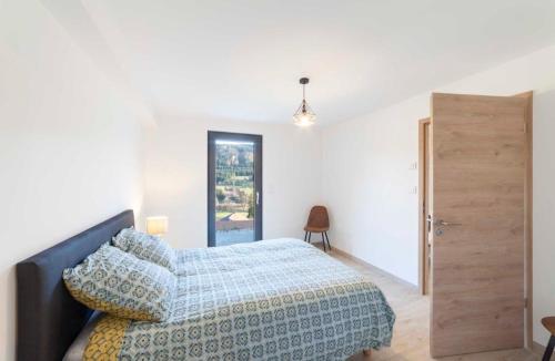 um quarto branco com uma cama e uma porta de madeira em Gîte Au Doubs Moment vue exceptionnelle et panoramique em Arçon