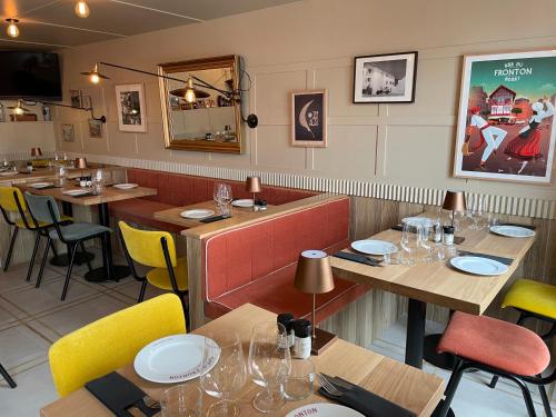 a restaurant with wooden tables and yellow chairs at Hotel du Fronton in Bidart