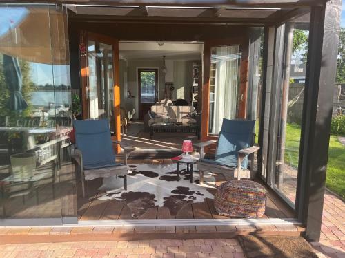a screened in porch with chairs and a table at The Outpost Lakehouse- enjoy our house at Reeuwijkse Plassen - near Gouda in Reeuwijk