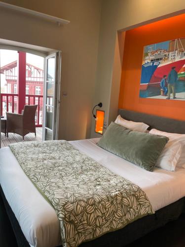 1 dormitorio con 1 cama con una pintura en la pared en Hotel du Fronton, en Bidart