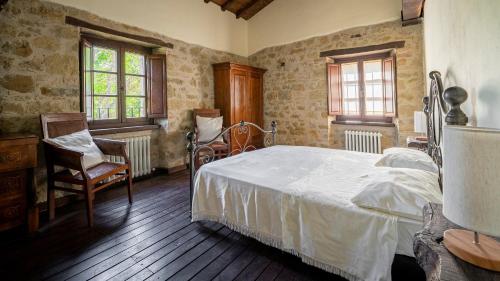 um quarto com uma cama, uma cadeira e janelas em Agriturismo I Pietrini em Perugia