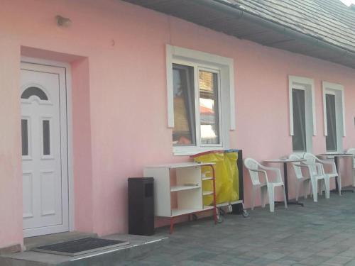un bâtiment rose avec des chaises, une table et une fenêtre dans l'établissement Chata Milan, à Hrabušice