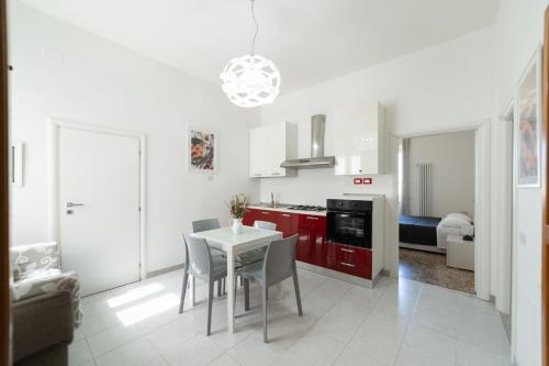 una cocina con armarios rojos y una mesa y sillas blancas. en La Casa Sul Melo, en Matera
