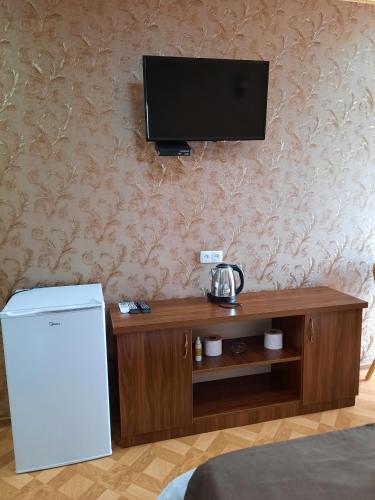 a room with a refrigerator and a television on a wall at Hotel LU-MA in Tbilisi City
