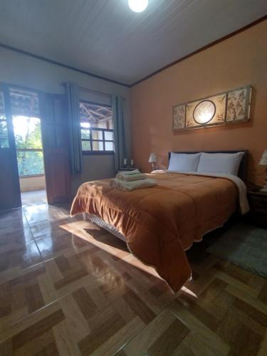 een slaapkamer met een groot bed en een houten vloer bij Chalés de Santana in Tiradentes