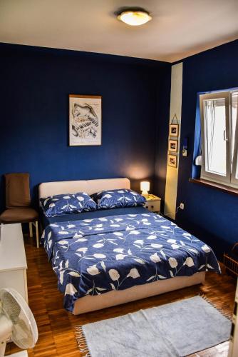a bedroom with a bed with a blue wall at apartman Iva in Krasica