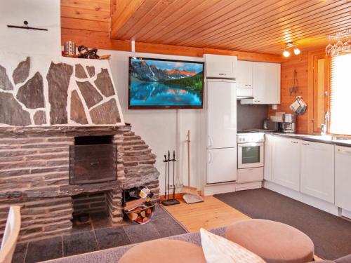 a kitchen with a stone fireplace with a flat screen tv at Holiday Home Lomasyväri 810 by Interhome in Nilsiä