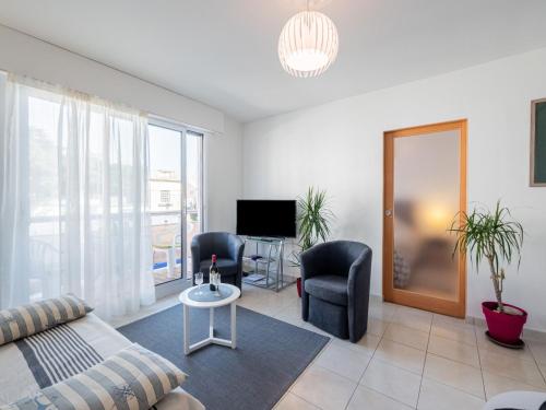 un salon avec un canapé, des chaises et une télévision dans l'établissement Apartment L'Hippocampe T2 balcon by Interhome, à Les Sables-dʼOlonne