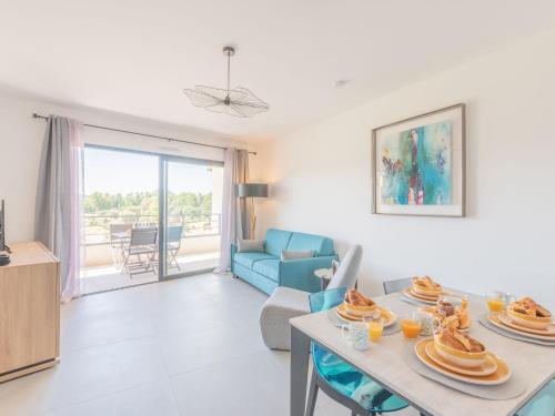un salon avec une table et un canapé bleu dans l'établissement Apartment Stanatura-4 by Interhome, à Porto-Vecchio
