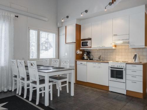 a kitchen with white cabinets and a table and chairs at Holiday Home Keskuskuja b4 by Interhome in Sirkka