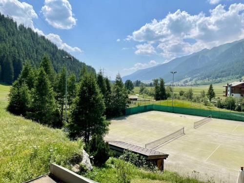 a tennis court in a field with mountains in the background at Hubertus 112 in Obergesteln