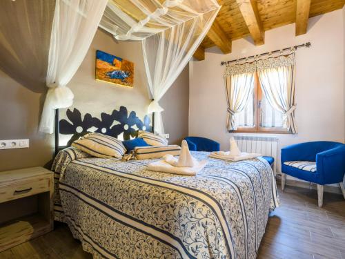 a bedroom with a bed and two blue chairs at Apartment El Ventanico by Interhome in Olocau del Rey