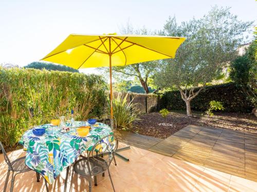 - une table avec un parasol jaune sur la terrasse dans l'établissement Holiday Home Le Mas d'Esquières 16 by Interhome, aux Issambres