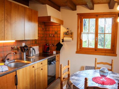 una cucina con tavolo, lavandino e finestra di Chalet Chalet Les Pitchounes by Interhome a Moleson