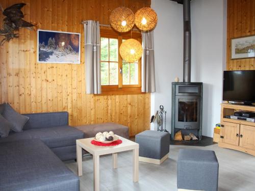 ein Wohnzimmer mit einem Sofa, einem Tisch und einem TV in der Unterkunft Chalet Chalet Les Pitchounes by Interhome in Moleson