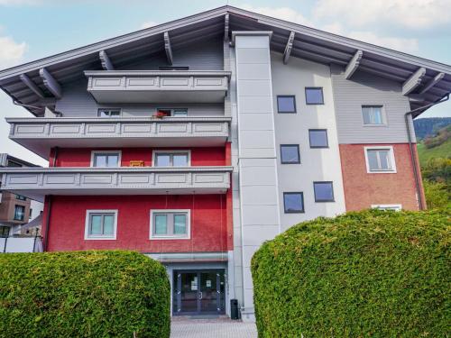 un edificio rosso e bianco con cespugli di fronte di Apartment Areitblick by Interhome a Zell am See