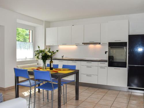 una cucina con armadi bianchi e un tavolo con sedie blu di Apartment Le Bolle by Interhome a Magadino
