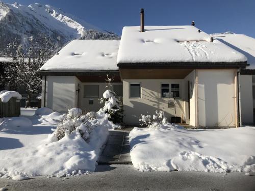 una casa cubierta de nieve con montañas en el fondo en Apartment Hostattstrasse 20 by Interhome en Engelberg