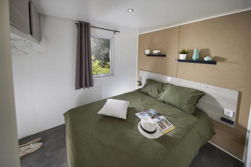 a bedroom with a green bed with a hat on it at Le Domaine du Bois Coquet in La Douze