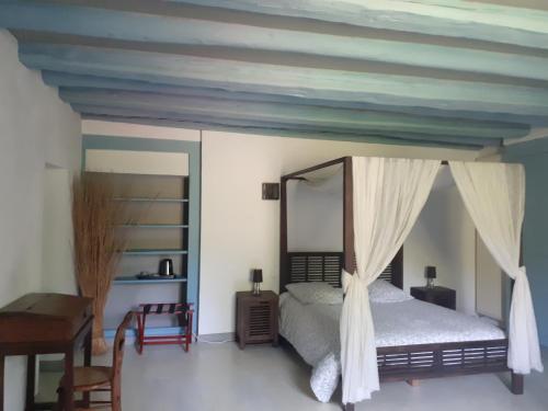 ein Schlafzimmer mit einem Himmelbett und einem Schreibtisch in der Unterkunft Moulin Chantepierre in Pont-dʼHéry