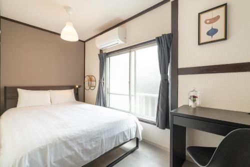 a bedroom with a bed and a desk and a window at Otuska house with 2BR near the Yamanote line in Tokyo