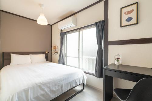 a bedroom with a bed and a desk and a window at Otsuka house with 2BR near the Yamanote line in Tokyo