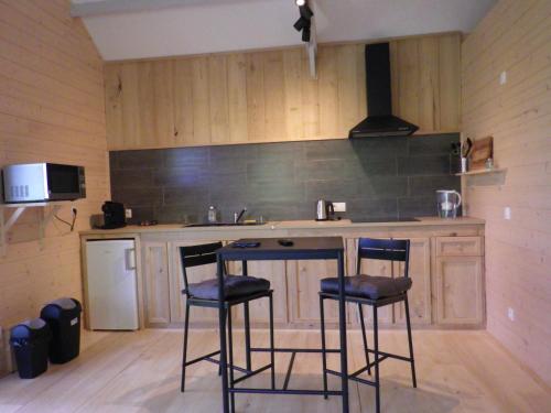 une cuisine avec un comptoir et deux tabourets de bar dans l'établissement maison sur pilotis, à Cazals