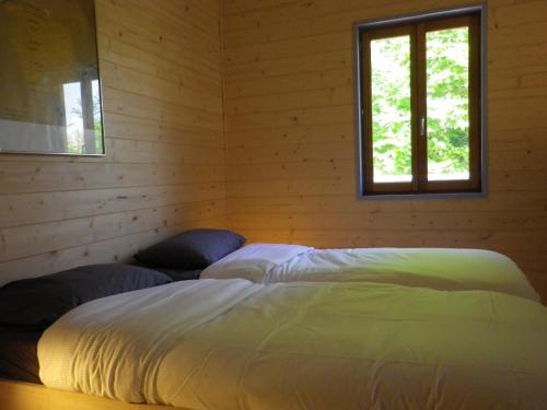 1 dormitorio con 2 camas y ventana en maison sur pilotis en Cazals