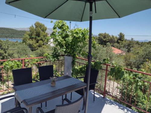 una mesa y sillas en un balcón con sombrilla en apartmani ANITA, Korčula, en Korčula
