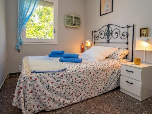 a bedroom with a bed with blue pillows and a window at Apartment Riumar by Interhome in Segur de Calafell