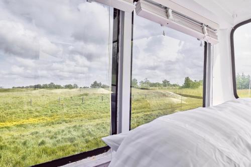 Un dormitorio con una ventana que da a un campo. en Beachbus Terra Incognito, en Westerland