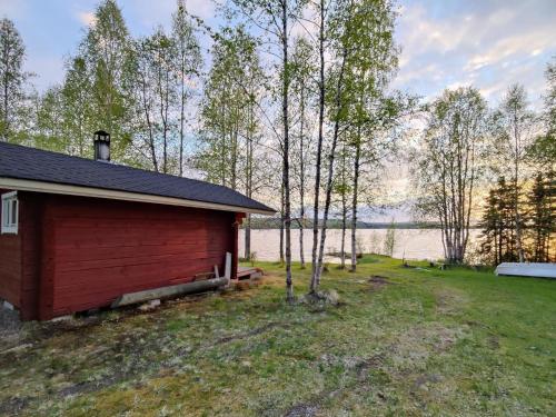 uma cabina vermelha com vista para um lago em Holiday Home Koivulahden reinola by Interhome em Raanujärvi