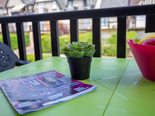 un livre et une plante en pot sur une table dans l'établissement Apartment Fleur Marine-30 by Interhome, à Cabourg