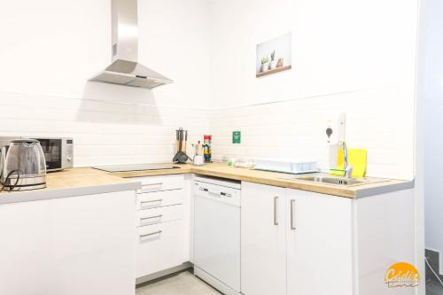 a white kitchen with white cabinets and a sink at Casa Rehala by Cadiz Time in Cádiz