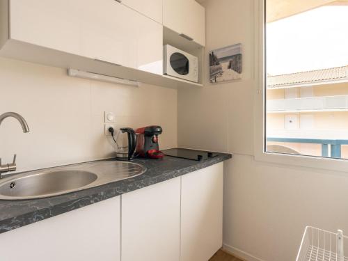 une petite cuisine avec un évier et une fenêtre dans l'établissement Apartment Les Hélianthes-2 by Interhome, à Lacanau-Océan