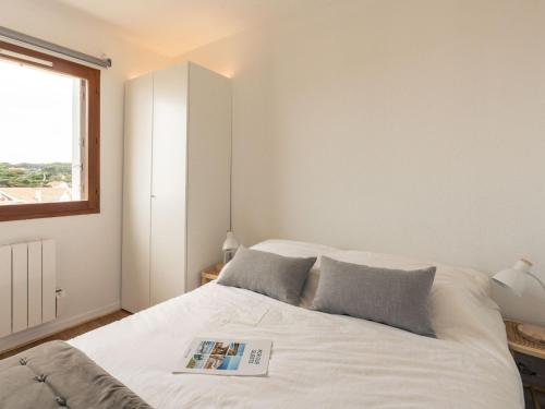 - une chambre avec un lit blanc et un livre dans l'établissement Apartment Les Hélianthes-2 by Interhome, à Lacanau-Océan
