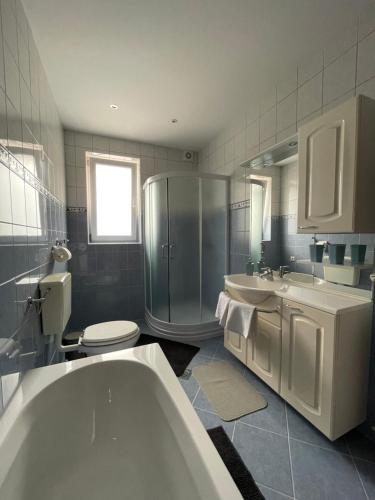 bagno con vasca, 2 lavandini e servizi igienici di Apartments B&S a Bled