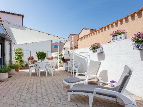 eine Terrasse mit weißen Stühlen und Tischen an einer Wand in der Unterkunft Holiday Home Le Canigounenc by Interhome in Sainte-Marie