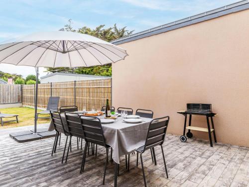 une table avec des chaises et un parasol sur une terrasse dans l'établissement Holiday Home Maison les Dunes by Interhome, à Saint-Lunaire
