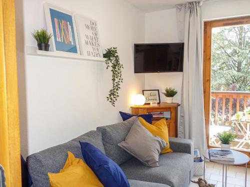 - un salon doté d'un canapé gris avec des oreillers bleus et jaunes dans l'établissement Apartment Le Martagon 007 by Interhome, à Saint-Gervais-les-Bains