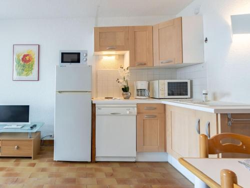 Elle comprend une petite cuisine équipée d'un réfrigérateur blanc et de placards. dans l'établissement Apartment Coudalère-Les Hébrydes-1 by Interhome, au Barcarès